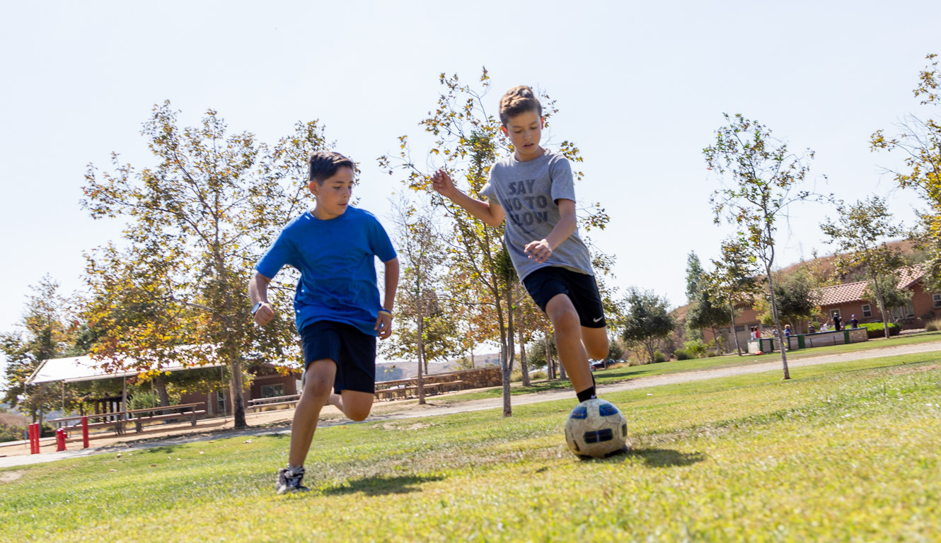 Two boys playing soccer on field at Irvine Ranch